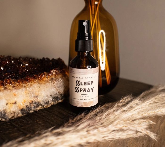 An image of the 'Sleep Spray' featuring a pipette, accompanied by a crystalline decoration and soft fronds