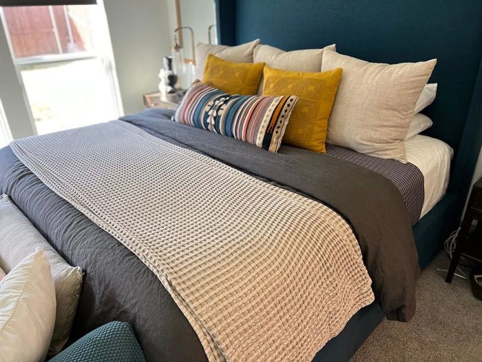 A well-arranged bed featuring a patterned throw and a variety of decorative pillows
