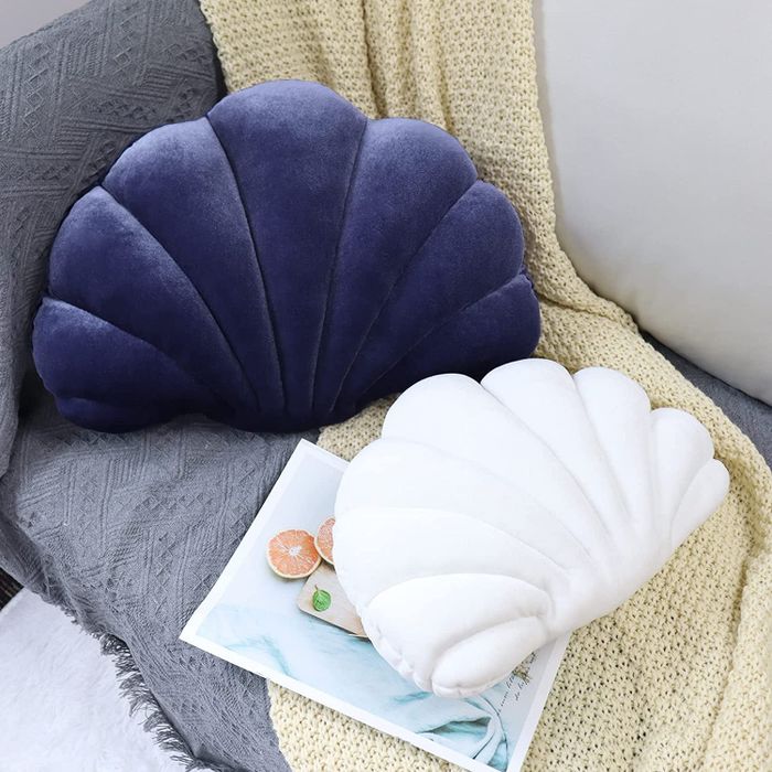 Both the purple and white variations of the seashell pillow on display.