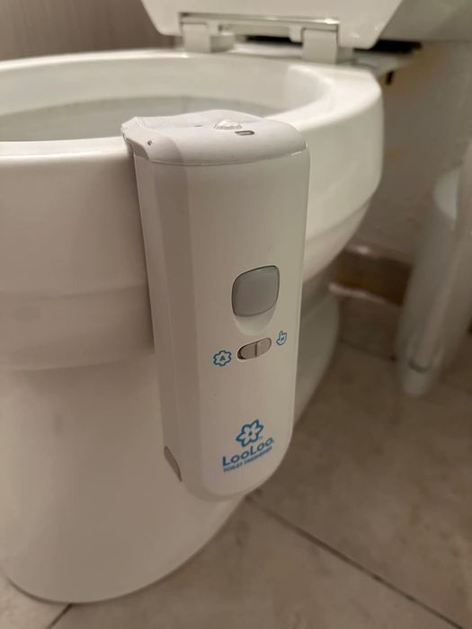 An automatic toilet bowl cleaner mounted on the side of a toilet.