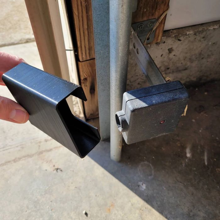 A shade being held in front of a garage door sensor to block sunlight.