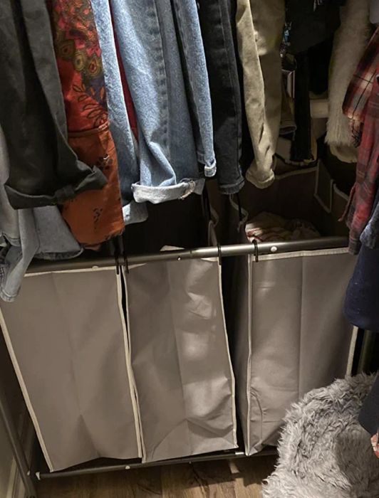 A metal cart with three beige bags stored neatly in a closet.