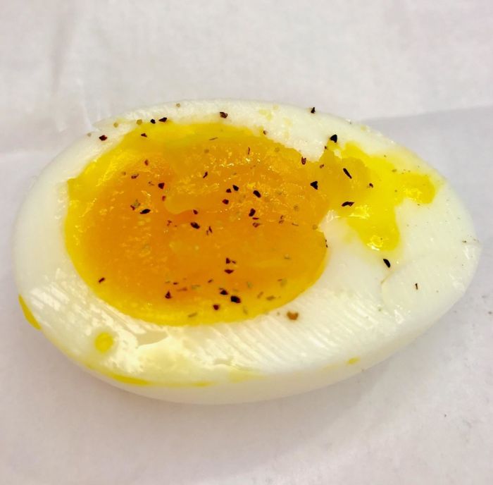 A medium-boiled egg sliced in half and sprinkled with salt and pepper