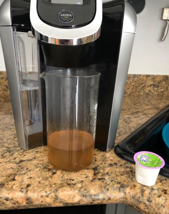 A Keurig cleaning pod beside a grimy bit of water that came out of the machine