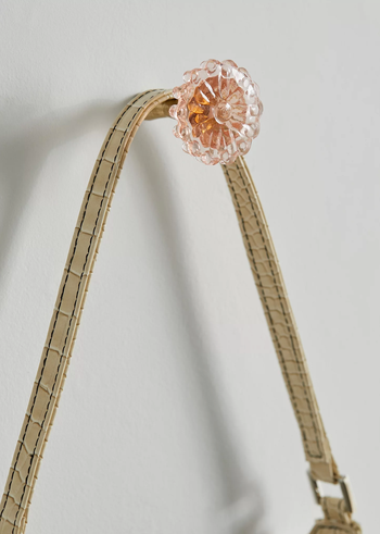 A floral-shaped wall hook with a stylish bag hanging from it, demonstrating its functional beauty.