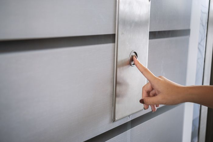 A person's finger pressing an elevator button