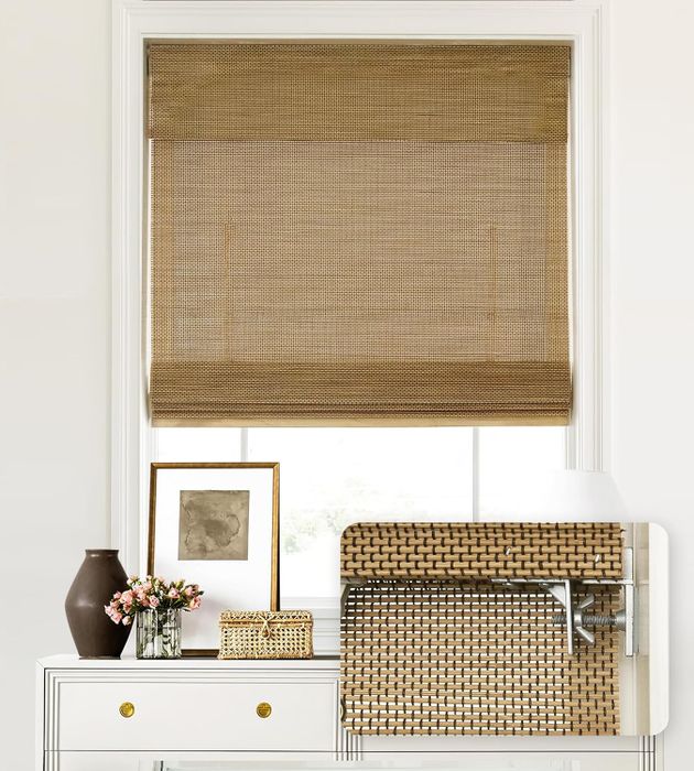 A window covered with woven bamboo shades, featuring a white desk with a vase of flowers, framed artwork, and a decorative basket. Swatches of two woven textures are displayed.