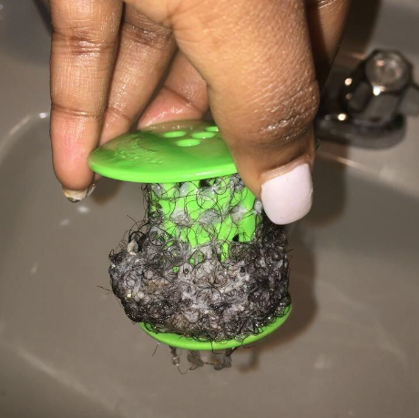 A reviewer showing off the natural hair coils trapped in their TubShroom