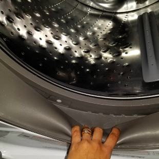 A reviewer showing the inside of their washing machine, now sparkling clean after using the product