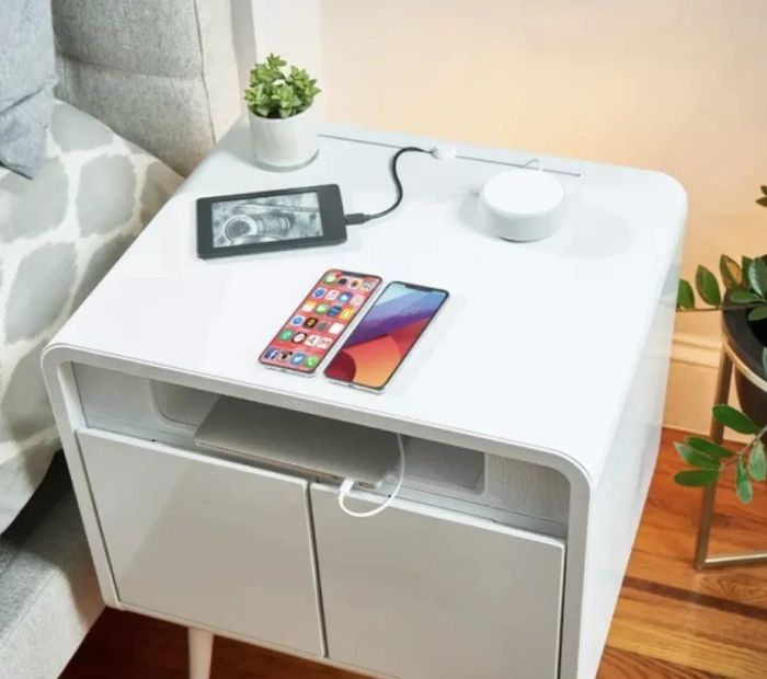 A white end table with devices charging on top of it