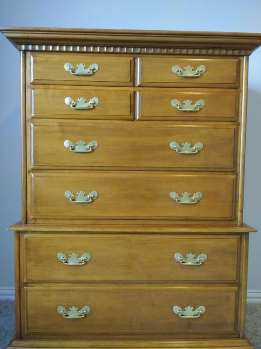 A wooden chest of drawers featuring nine brass-handled drawers, ideal for bedroom storage. Featured in a shopping guide for home furniture.