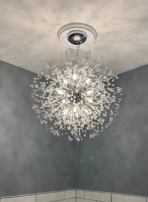 A close-up of the chandelier glowing above a bathroom sink