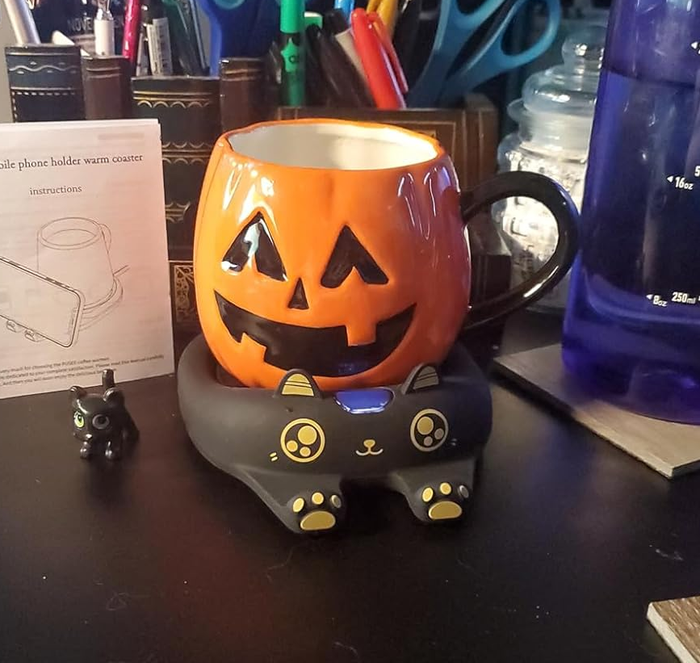 A flat black tray under a jack-o'-lantern-themed mug