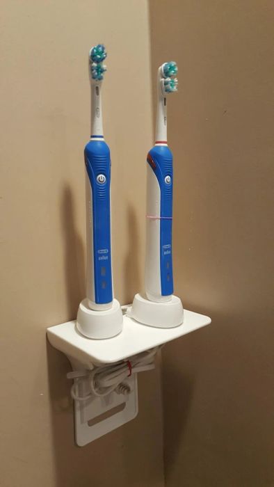 reviewer's photo of an outlet shelf with two electric toothbrushes neatly stored on it