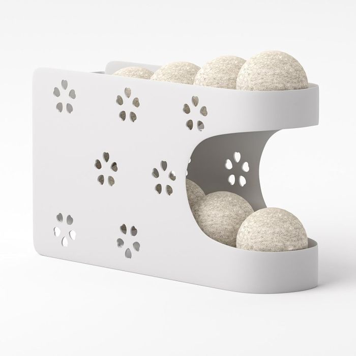 A white double-decker storage organizer holding dryer balls.