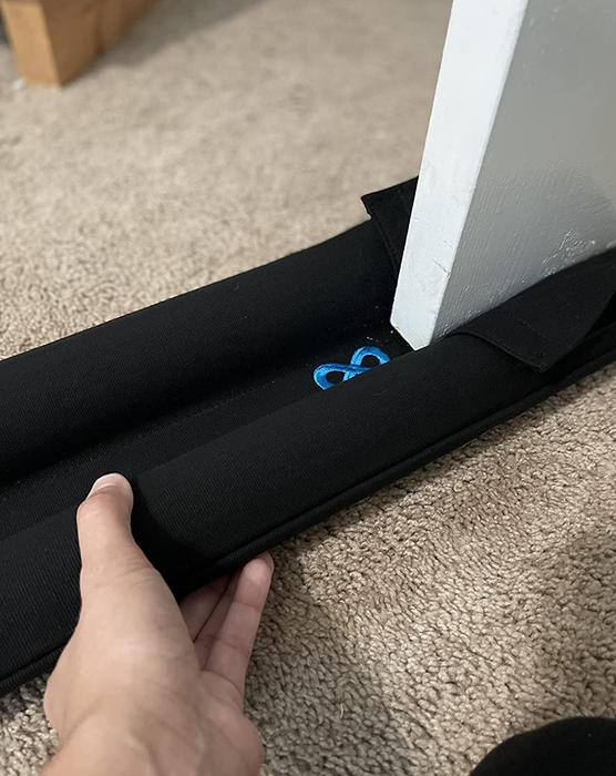 A reviewer putting the door draft stopper into place on the door