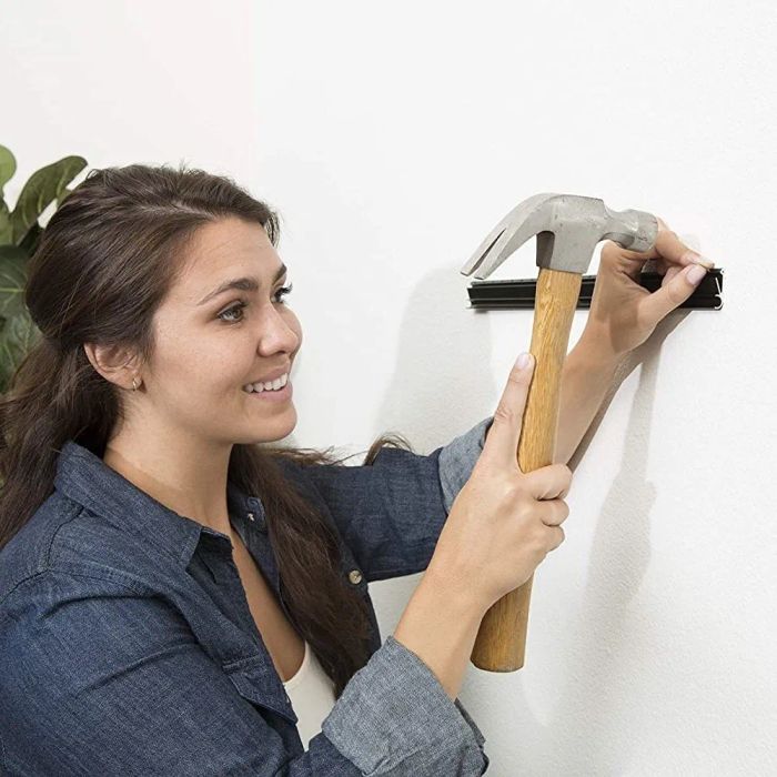 A person securing a bracket to the wall with nails.