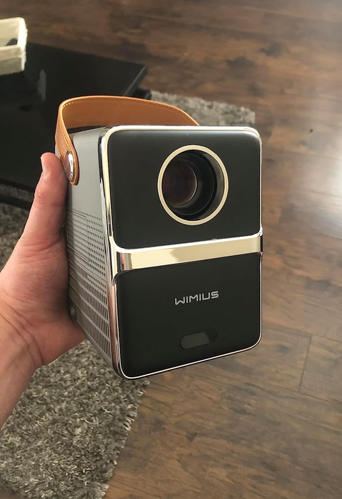 A reviewer proudly holding up the compact projector.