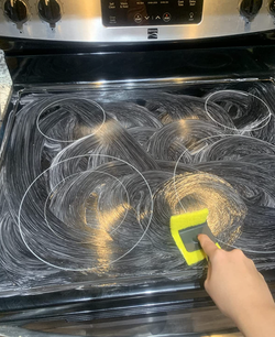 A reviewer cleaning their stovetop using the cleaning kit