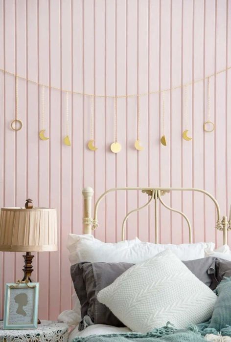 A string of garland draped over a headboard with delicate moon phase charms hanging from it.