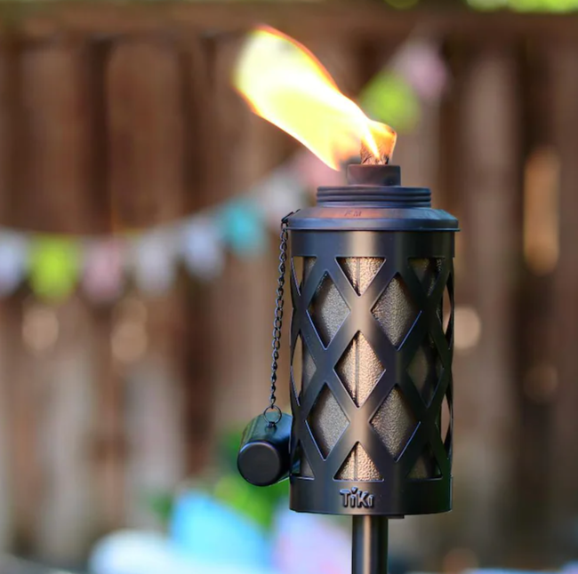 A photo of a Tiki torch burning citronella oil in the garden.