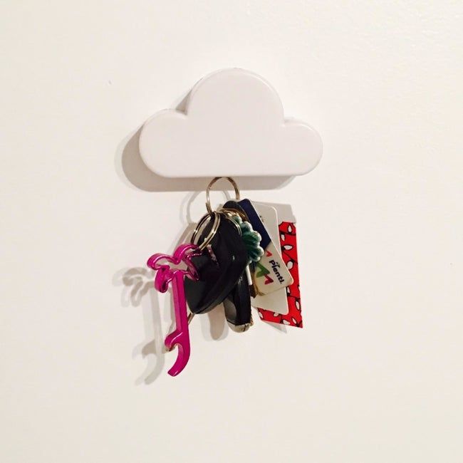 A reviewer's photo showing the white cloud-shaped key holder mounted on a wall, with a large set of keys hanging on it.