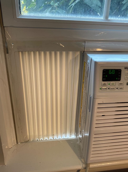 A photo from a reviewer showing the tape applied around the edges of a window air conditioner unit