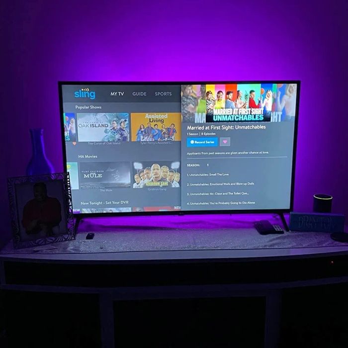 A reviewer displays the LED lights behind a TV, glowing in purple.