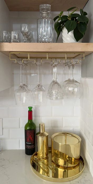 A reviewer's gold stemware holder mounted beneath a shelf, neatly displaying various sizes of glasses.