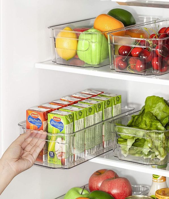 A model demonstrates how to pull the handle of a clear organizer in a fridge packed with fruits, veggies, and juice boxes, highlighting the convenience of the setup.