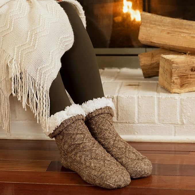 A cozy fireplace scene with a person wearing knitted socks and a fringed blanket, highlighting the warmth and comfort perfect for a winter shopping article.