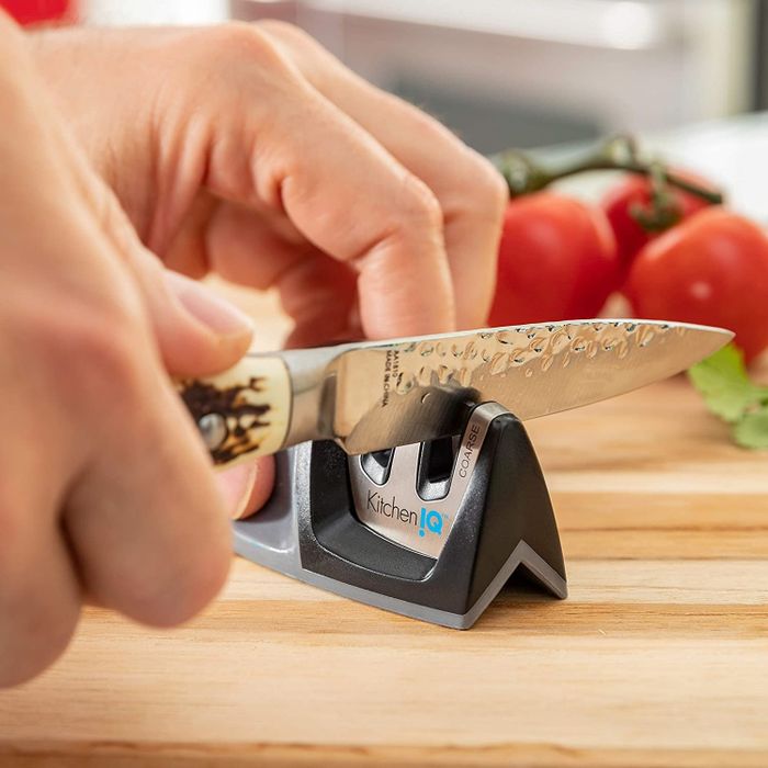 A pair of hands sharpening a knife using the black knife sharpener.