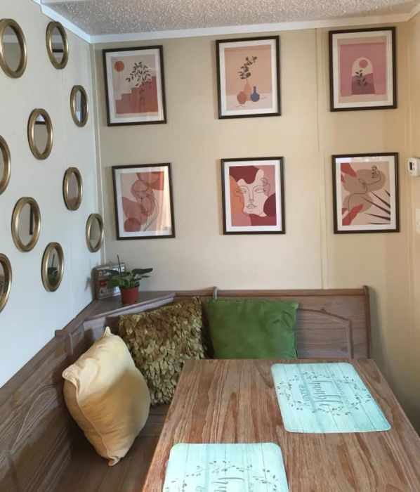 Another reviewer's cozy dining nook, with a wooden bench, decorative pillows, and the six prints adorning the wall.