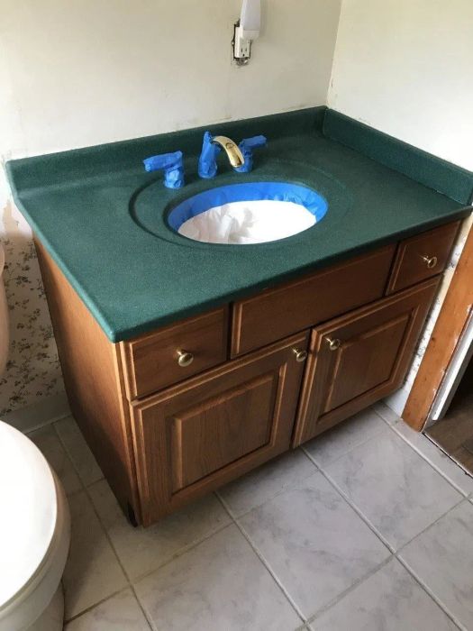 A reviewer's image showing the worn-out, green bathroom vanity top.
