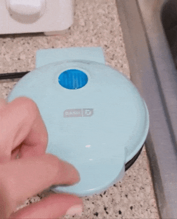 Gif of reviewer opening the mini aqua appliance to reveal a freshly cooked waffle