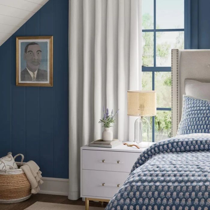A white blackout curtain panel hanging in a bedroom window, blocking out all light.