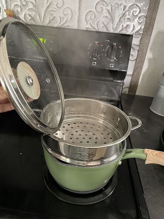 A reviewer showcases the heated pot and steamer with the lid removed, highlighting its versatility.