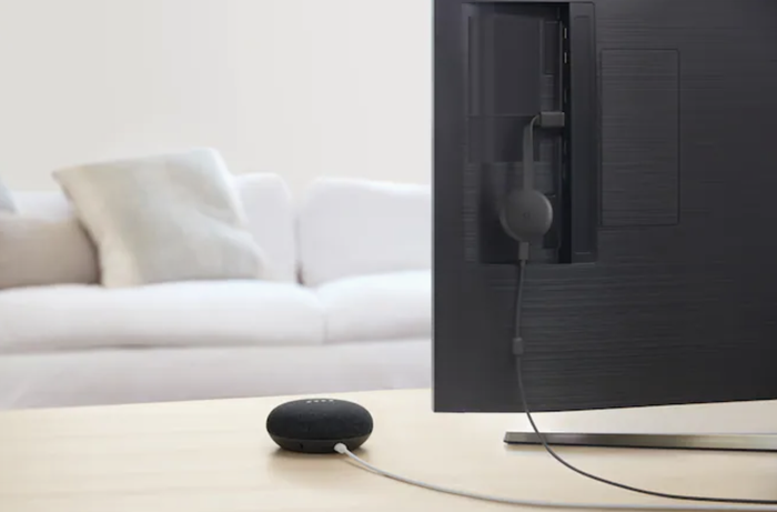 The Google Nest Mini placed on a console table behind a TV setup