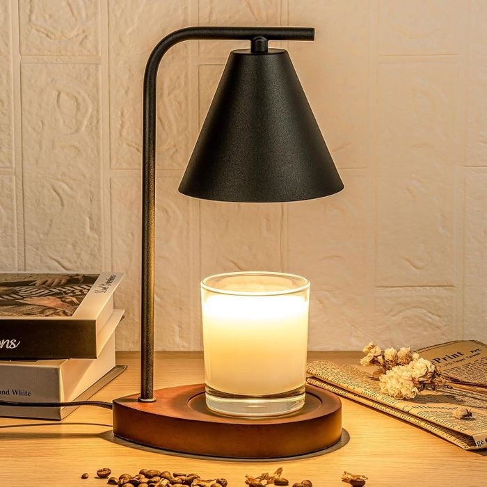 A chic lamp warming a candle on a wooden table, surrounded by books and dried flowers, setting a cozy shopping mood.