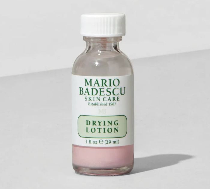 A bottle of Mario Badescu Drying Lotion with a white cap, set against a neutral backdrop