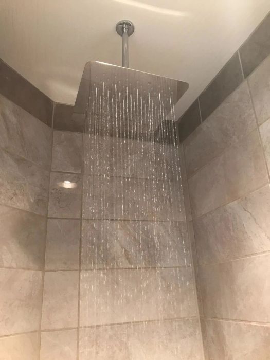 A view of the rainfall shower head from below, installed from the ceiling.