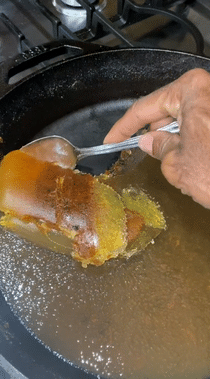 Gif of a reviewer using a spoon to remove oil from a pan, demonstrating the solidification process