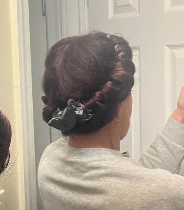 A reviewer with their hair wrapped around a heatless curling rod, secured with scrunchies