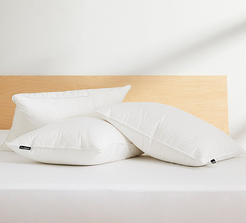Three plush pillows neatly stacked on a bed.