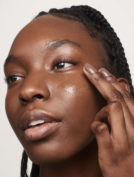 Model applying Glossier Perfecting Skin Tint