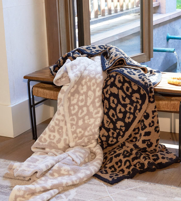 Leopard print blankets draped over a bench beside a window, adding to the cozy and chic atmosphere of home decor.