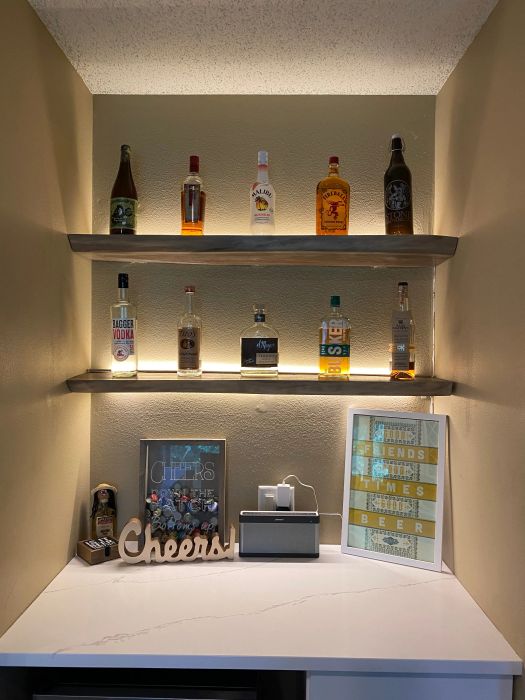 Reviewer photo showing lights installed under floating shelves with liquor bottles.