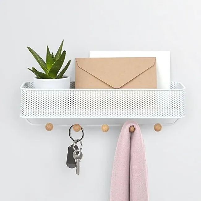 A mail organizer with a perforated metal bin and five hooks with wooden knobs underneath, mounted on a wall.