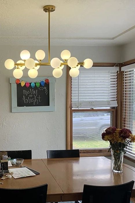 A reviewer's chandelier hanging above a mid-century modern dining table, creating a stylish atmosphere.