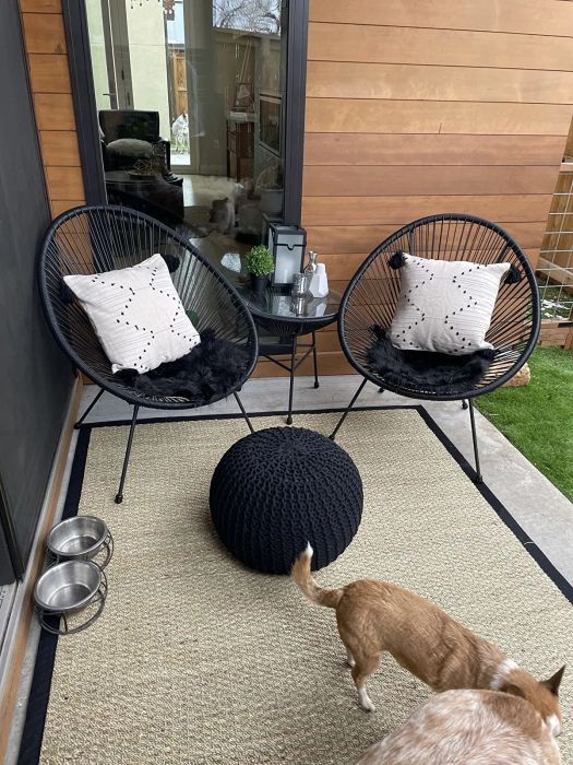 A reviewer shows off the black set beautifully arranged on a small patio.